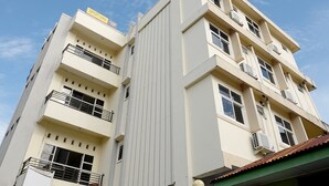 A multi-story building with balconies, air conditioning units, and a sign that reads "SPOT ON".