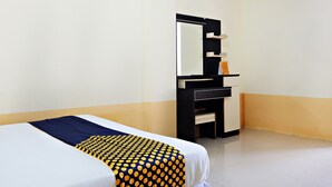 A hotel room with a bed, a dresser, a mirror, and an air conditioning unit.