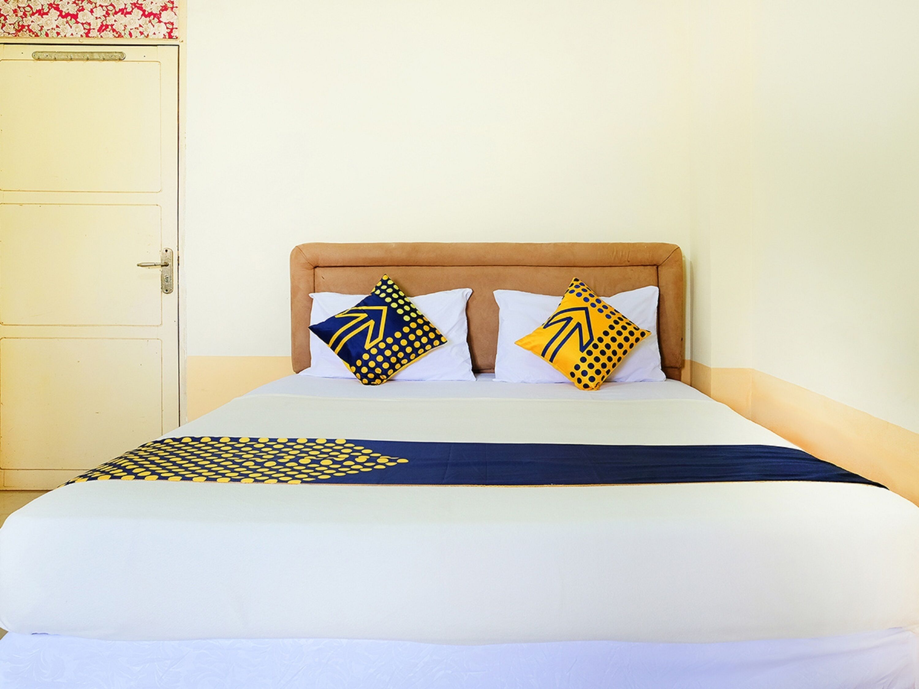 Ein Bett mit Kopfteil, zwei Kissen mit geometrischen Mustern und einer passenden Tagesdecke.