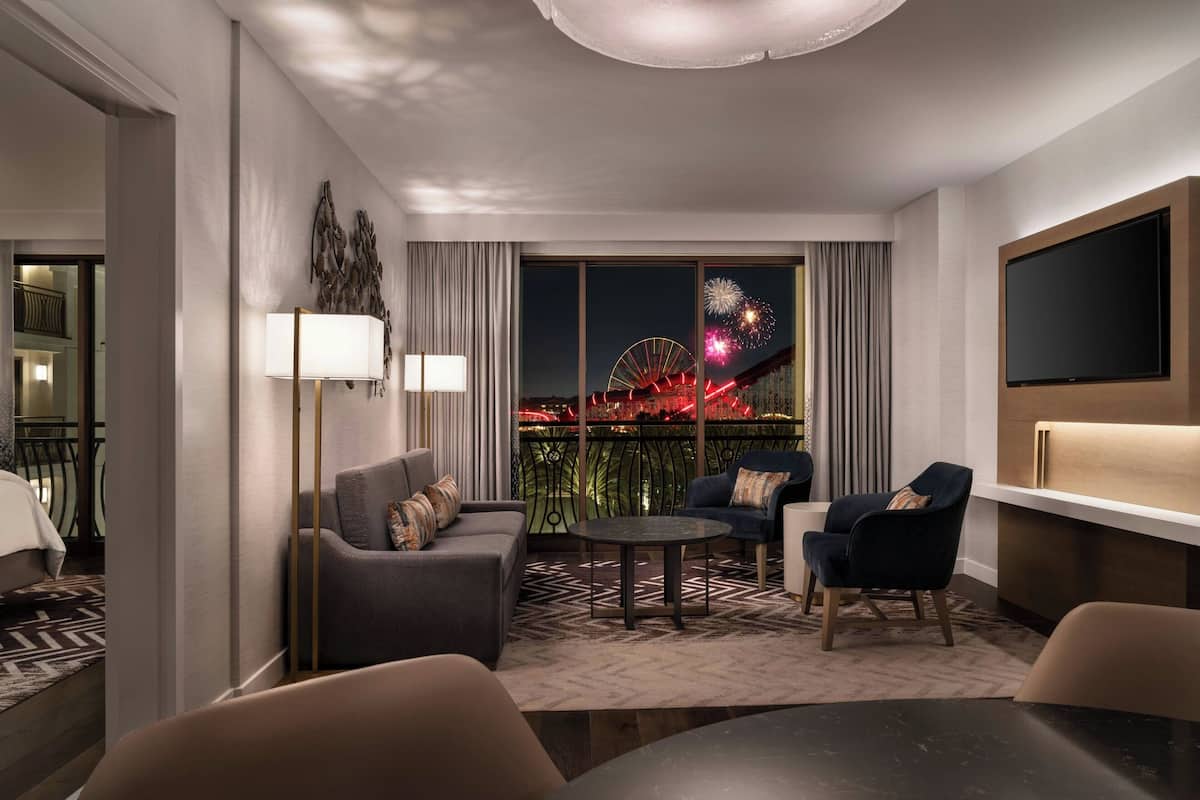 Una habitación de hotel moderna con balcón, televisor grande y vistas a fuegos artificiales.