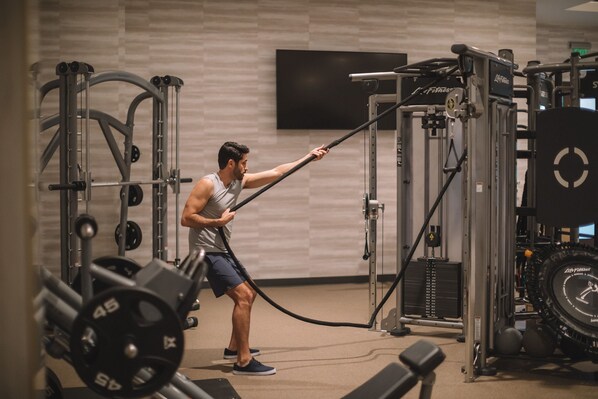 A gym with weightlifting equipment, including a cable machine and weight plates. - The Westin Anaheim Resort (Anaheim)