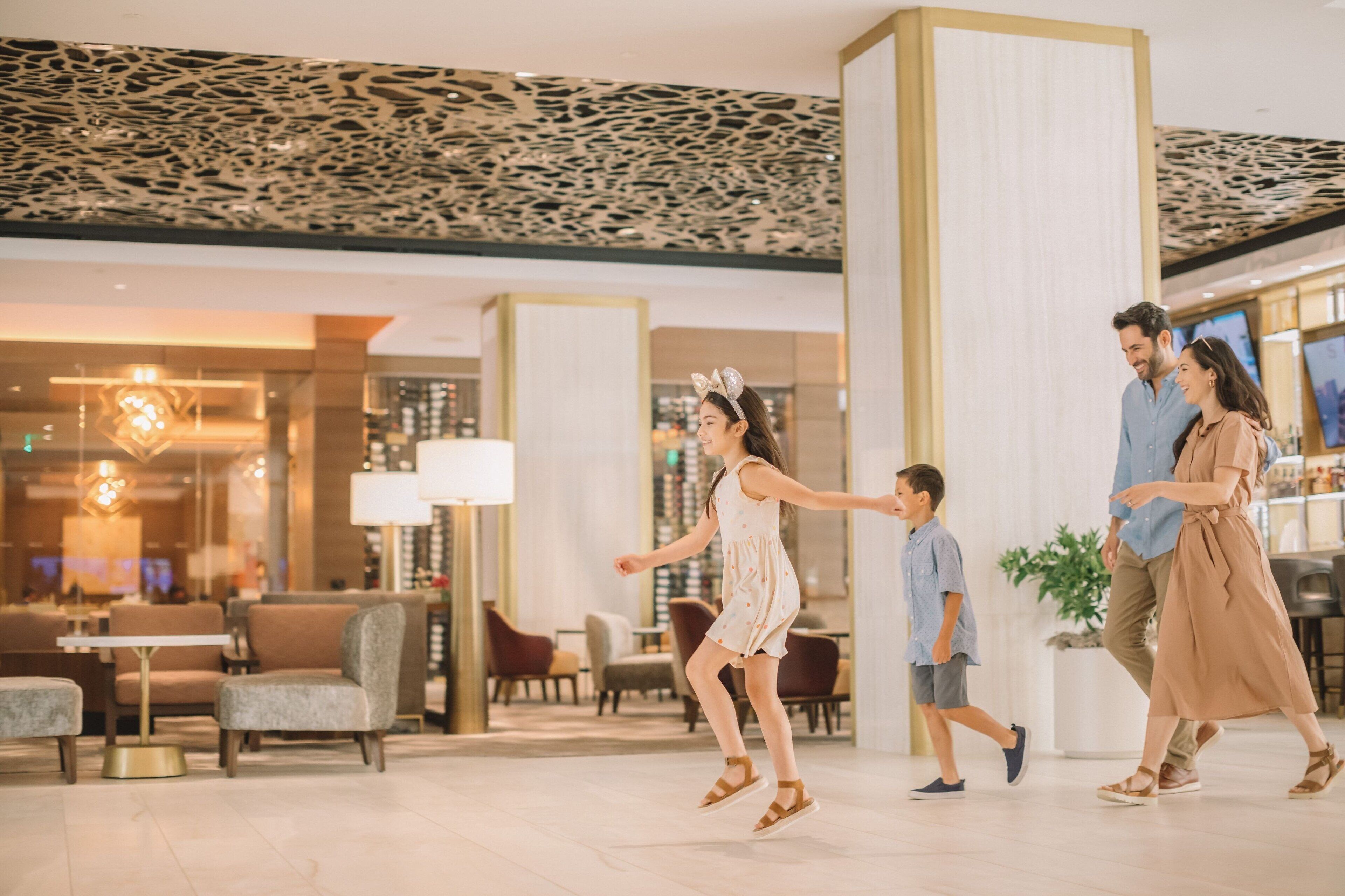 A modern hotel lobby with a high ceiling, comfortable seating, and a central column.