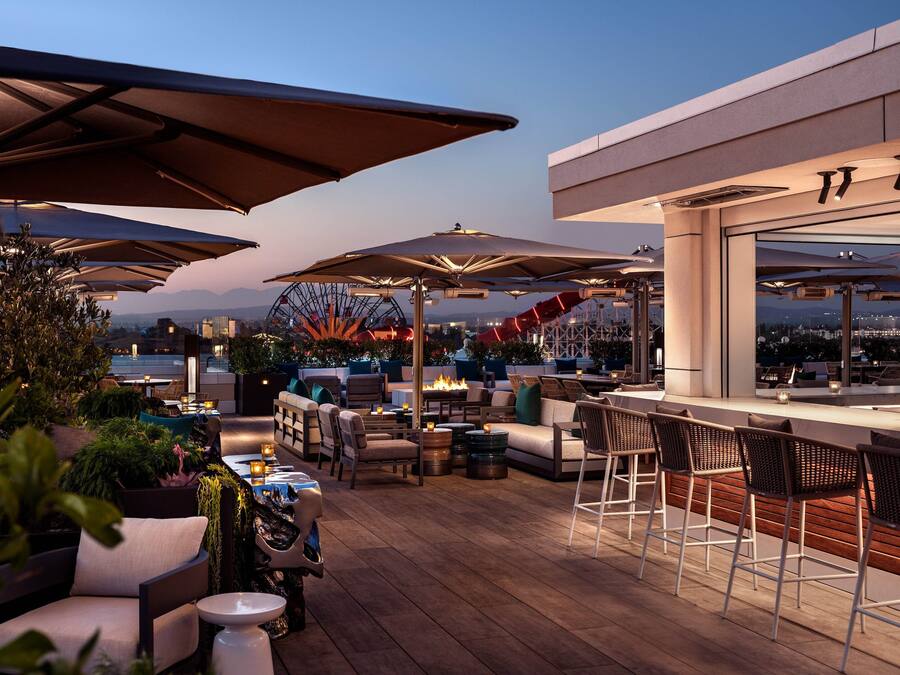 Un espace extérieur aménagé avec des parasols, des canapés et des tabourets de bar.