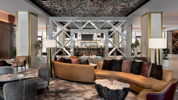 A modern lounge area with a curved sofa, armchairs, and a central bar with a fireplace.