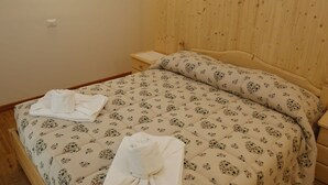 A bedroom with a wooden headboard, a bed with floral bedding, a nightstand, and a bedside lamp. - Cosy apartment for 3 guests with WIFI, TV, patio and pets allowed (Raveo)