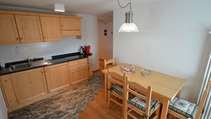 A compact kitchen with wooden cabinets, a granite countertop, and a dining table with chairs. - Beautiful apartment for 3 guests with WIFI, TV, patio and pets allowed (Raveo)