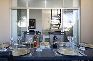Une table à manger dressée pour un repas, avec des assiettes, des couverts et des verres à vin.