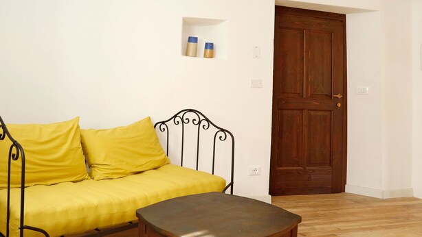 Une pièce avec un lit, une petite table et une porte en bois.
