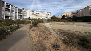 A residential area with modern apartment buildings, a curved pathway, and sparse vegetation. - STUDIO 4 PERS AVEC PKG BORD DE PLAGE VUE MER (Sète)