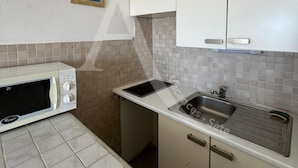 A compact kitchen with a microwave, sink, and tiled backsplash. - STUDIO 4 PERS AVEC PKG BORD DE PLAGE VUE MER (Sète)