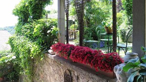 A stone wall with a planter of red flowers, a metal gate, and a stone sculpture of a rabbit.