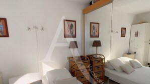 A bedroom with two beds, a wardrobe, and a mirror.