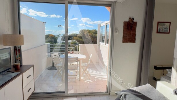 A bedroom with a sliding glass door leading to a balcony with a table and chairs.