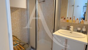 A bathroom with a glass-enclosed shower, a white sink, and a mirror above it.