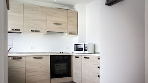 A modern kitchen with light wood cabinets, a built-in oven, and a microwave. - Beautiful apartment for 4 people with WIFI, TV, patio and pets allowed (Ovasta)