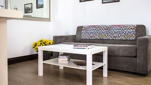 A living room with a grey sofa, a white coffee table, and a mirror on the wall. - Beautiful apartment for 4 people with WIFI, TV, patio and pets allowed (Ovasta)