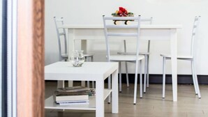 A dining area with a white table and chairs, a framed picture on the wall, and a stone wall feature.