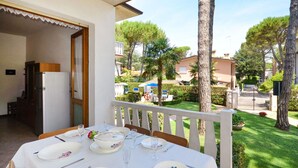 An outdoor dining area with a table set for four, overlooking a well-maintained garden and residential buildings.