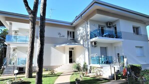 Un edificio residencial de dos pisos con un balcón en el nivel superior, un pequeño porche delantero y un camino de entrada a la puerta.