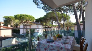 Un balcón con mesa lista para comer, con vistas a una zona residencial con árboles y casas.
