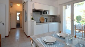 Una cocina moderna con armarios blancos, un microondas integrado y un ventanal grande.