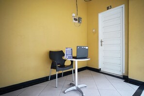 A small room with a white door labeled "B3," a black chair, a small table with a laptop, and a sign on the wall.