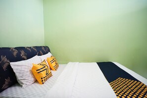 A bed with a white and black checkered bedspread, two pillows with a yellow and black pattern, and a dark blue headboard with a leaf design.