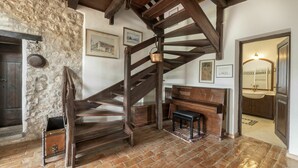 A rustic room with a wooden staircase, stone wall, and a piano. - Beautiful apartment in villa for 4 guests with A/C, pool, WIFI, TV and terrace (Povoletto)