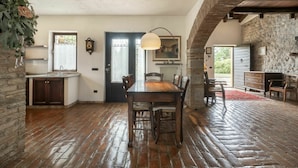 A rustic interior with a wooden dining table, chairs, a kitchen with a sink, and a stone wall. - Beautiful apartment in villa for 4 guests with A/C, pool, WIFI, TV and terrace (Povoletto)