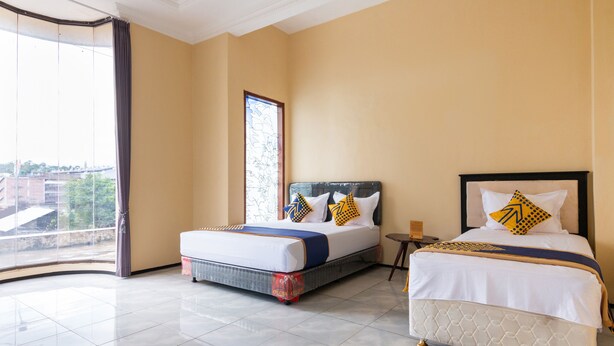 Une chambre d’hôtel avec deux lits, une grande fenêtre et une vue sur la ville.