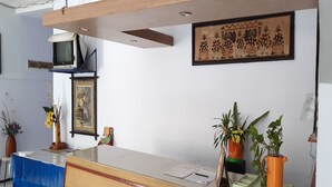 Un espace d’accueil comprenant un comptoir, un téléviseur fixé au mur et une œuvre d’art encadrée au-dessus du comptoir.