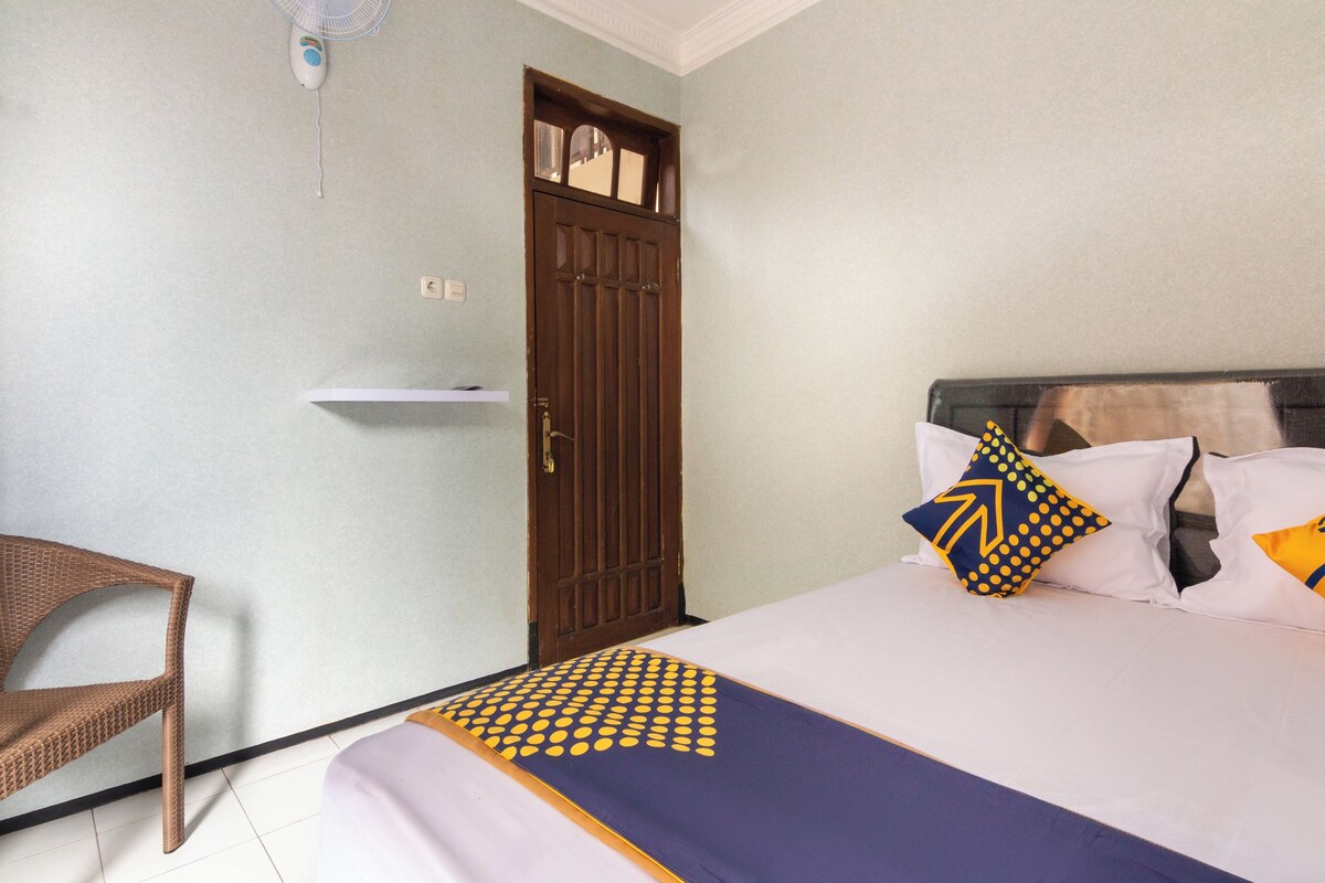Una habitación con una cama, una silla, una puerta y un pequeño estante.