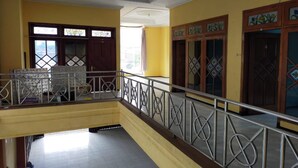 Un immeuble à plusieurs étages aux murs jaunes, doté d’un balcon avec des balustrades en métal et de portes en bois décoratives agrémentées de vitraux.
