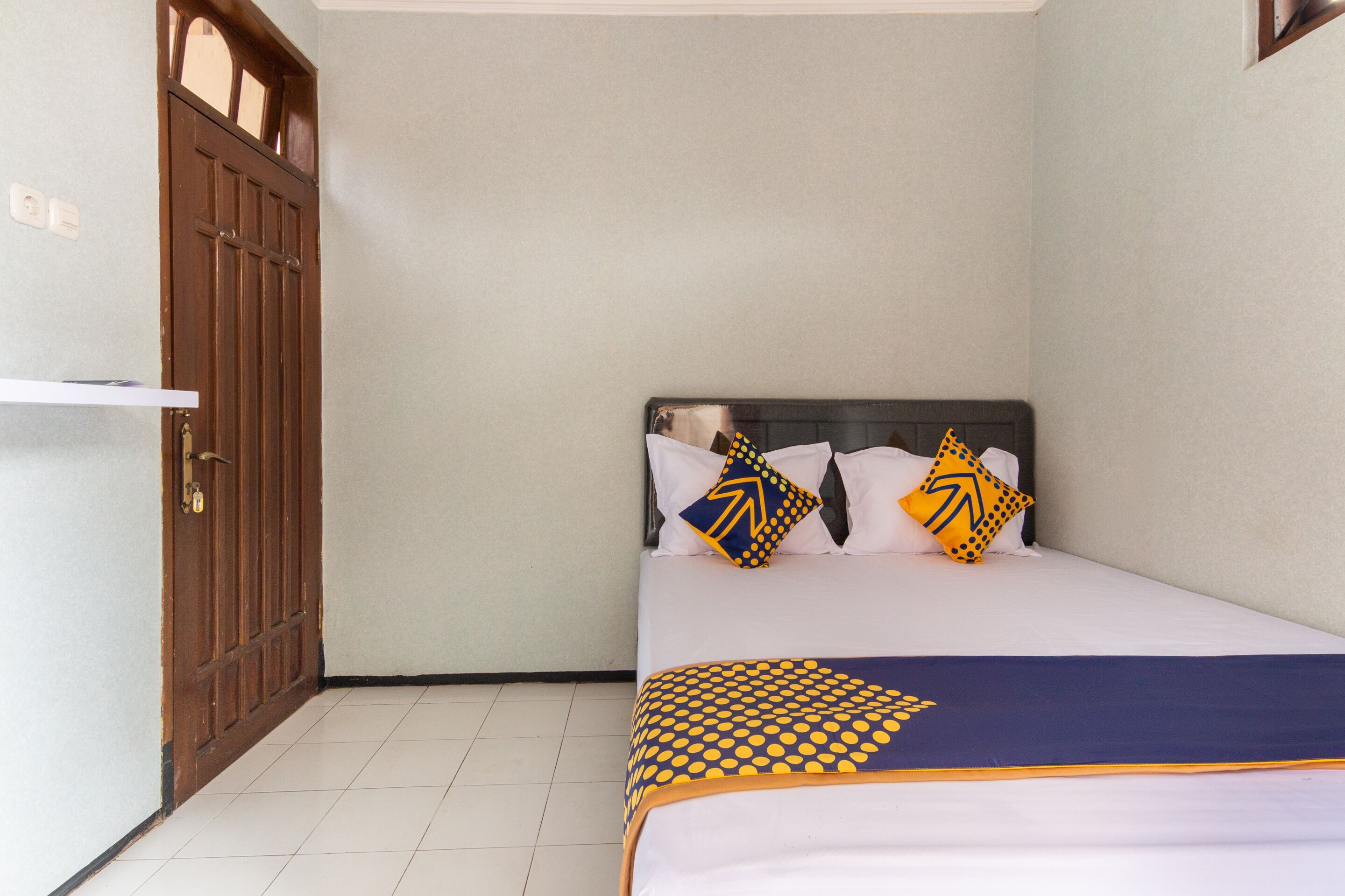 Quarto com cama, almofadas e uma porta.