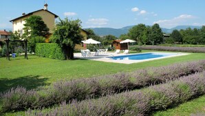 A backyard with a swimming pool, outdoor seating, and a house. - Cosy apartment in villa for 4 guests with A/C, pool, WIFI, TV and terrace (Povoletto)