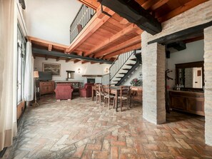 Un vaste espace de vie doté d’un parquet à motifs en chevrons, de meubles en bois, d  ’une cheminée et d’un escalier menant à un niveau supérieur.