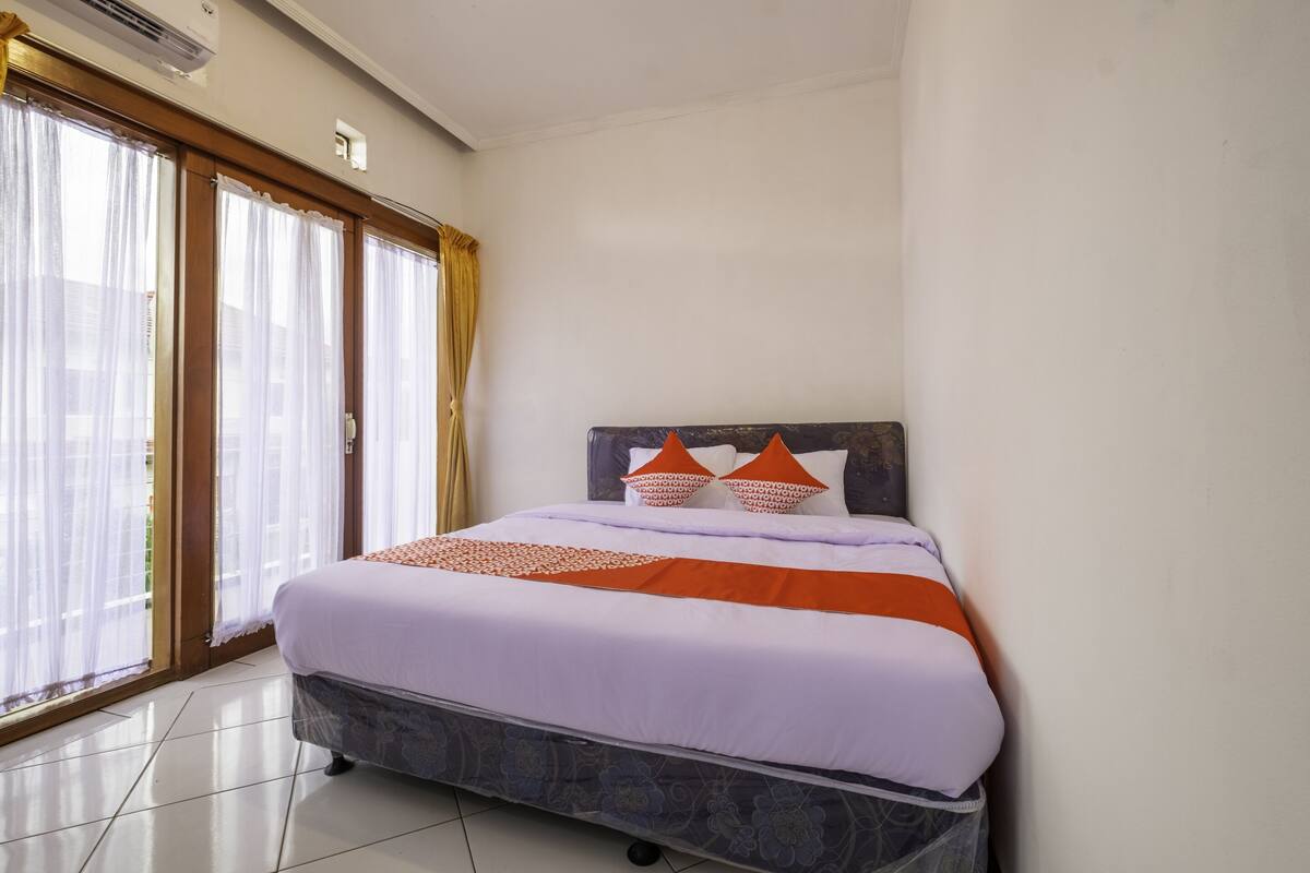 Une chambre d’hôtel avec un lit, une fenêtre avec des rideaux et une vue sur l’extérieur.