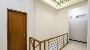 Um corredor com porta de madeira, guarda-corpo de metal e claraboia.