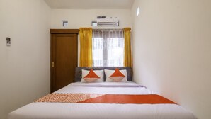Quarto de hotel com cama, cortinas, aparelho de ar condicionado e porta.