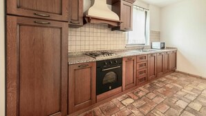 A kitchen with wooden cabinets, a stove, an oven, and a microwave. - Cosy apartment in villa for 4 people with A/C, WIFI, pool, TV, terrace and pets allowed (Povoletto)