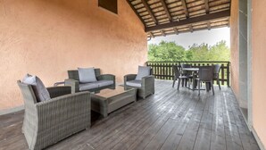 An outdoor patio with wicker furniture, a glass-top table, and a view of greenery. - Cosy apartment in villa for 4 people with A/C, WIFI, pool, TV, terrace and pets allowed (Povoletto)