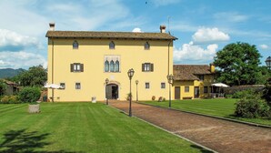 A yellow building with a tiled roof, a central entrance, and a paved courtyard. - Cosy apartment in villa for 4 people with A/C, WIFI, pool, TV, terrace and pets allowed (Povoletto)