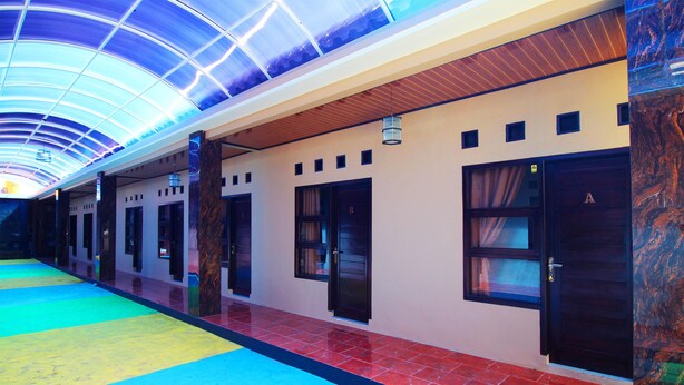 A hotel corridor with a colorful floor, a wooden ceiling, and a door with a number sign. - OYO 2630 Wisma Fahza Syariah (Bandar Lampung)