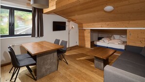 Ein modernes Interieur mit Holzboden, einer Essecke mit Tisch und Stühlen, einer Couch und einem Bett mit Kopfteil.