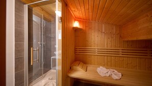 Eine Holzsauna mit einem gläsernen Duschbereich und einer Sitzbank.