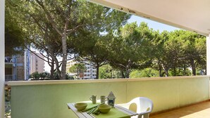 Ein Balkon mit Tisch und Stühlen, der auf eine von Bäumen gesäumte Gegend mit Gebäuden im Hintergrund blickt.