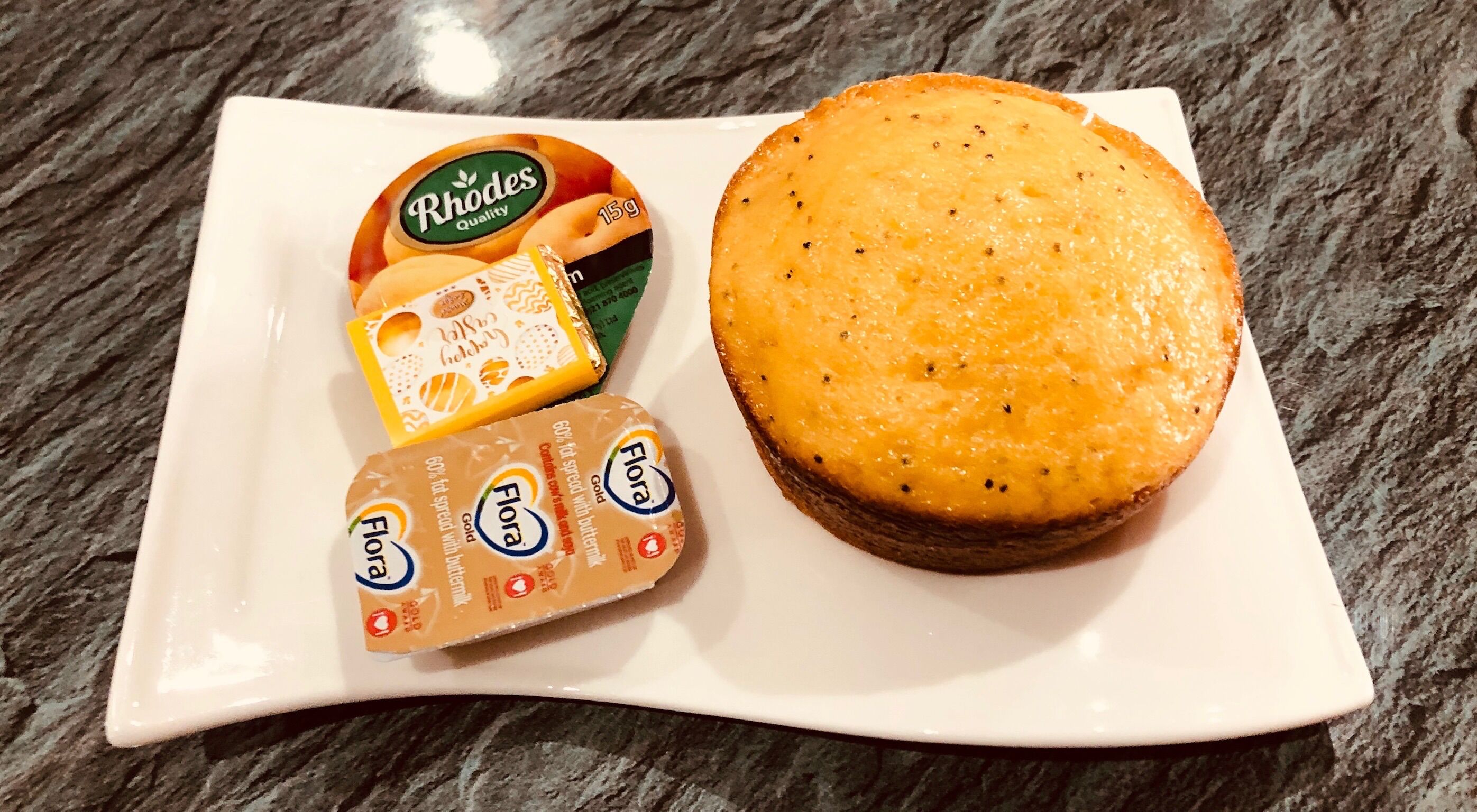 A plate with a large sandwich and three packaged food items.