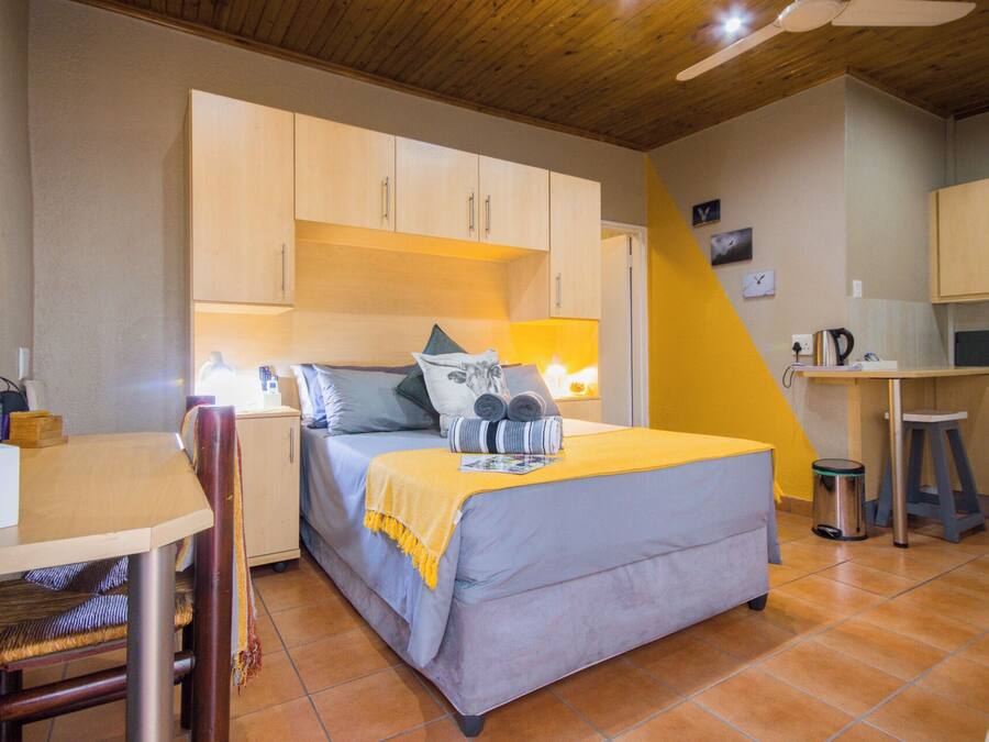 Une petite chambre comprenant un lit, un bureau et une kitchenette.