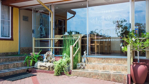 Ein Hotel mit Glasfassade, Sitzgelegenheiten im Freien und einem großen Topfpflanzen.