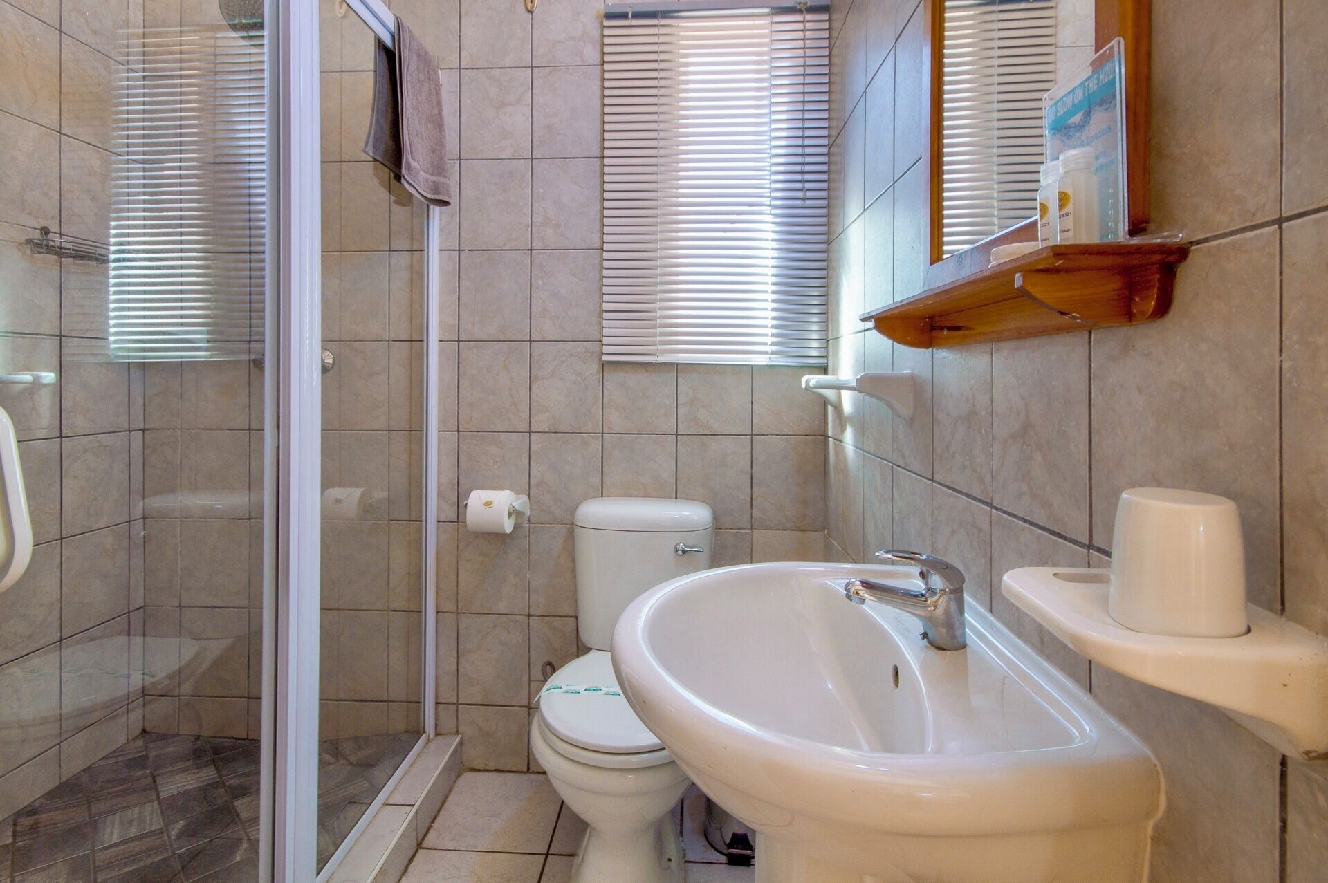 A bathroom with a shower, toilet, sink, and a towel rack.